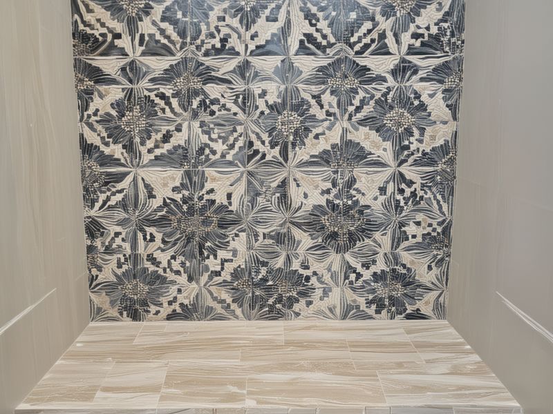 Professional ceramic tile installation in luxury bathroom showing precise layout with decorative borders and custom mosaic patterns